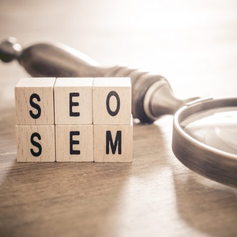 Old Magnifying Glass Lying Next to SEO And SEM Blocks In Monochrome Colors - Search Engine Optimization And Marketing Concept